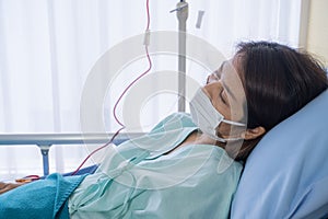 Asian woman is sick has a high fever, sneezing, is recuperating in the patient`s dress lay on the patient bed in the hospital wit