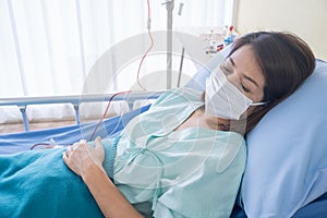 Asian woman is sick has a high fever, sneezing, is recuperating in the patient`s dress lay on the patient bed in the hospital wit