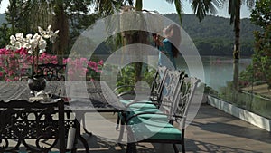 Asian woman in silk robe is relaxing breakfast on the big private terrace