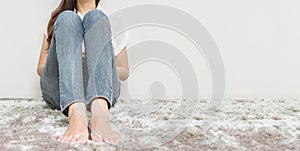 Asian woman sit on gray carpet floor with white cement textured background at the corner of house with copy space