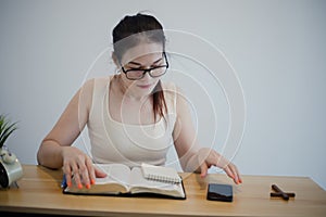 Asian woman sits and makes notes while studying the bible. Concept of hope, faith, christianity, religion, church online