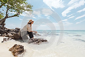 Asian woman sitting on the beach looking at the amazing sea and enjoying with beautiful nature in her vacation.