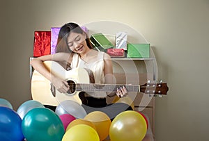 Asian woman sitting in bed play acoustic guitar at home