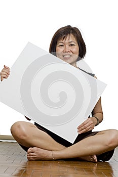 Asian woman sitting down holding placard for text