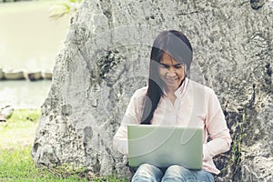 Asian woman sitting green park using laptop computer. Woman working on laptop happy entrepreneur business using notebook with