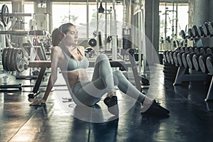 Asian woman sitting on on gym floor