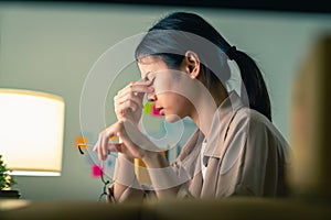 Asian woman sitting and holding glasses with hands touch the eyebrows.