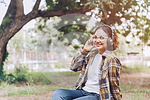 Asian woman sitting and listening to music in the garden