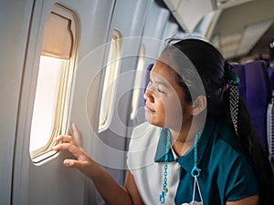 Asian woman sitting looking out of plane window.