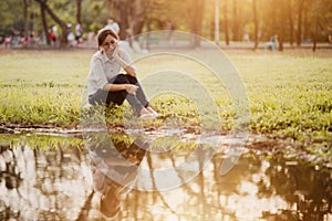 Asian woman sitting near swamp in the park.