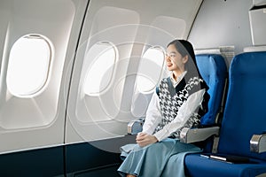 Asian woman sitting in a seat in airplane and looking out the window going on a trip vacation travel concept.Capture the allure of