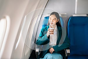 Asian woman sitting in a seat in airplane and looking out the window going on a trip vacation travel concept.Capture the allure of