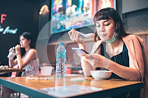 Asian woman sitting separated in restaurant eating food .keep social distance for protect infection from coronavirus covid-19,