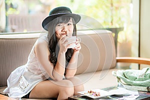 Asian woman sitting on sofa with coffee
