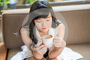 Asian woman sitting on sofa with coffee