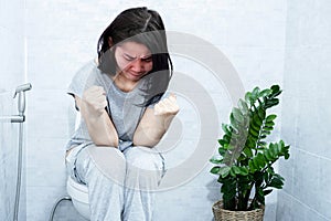 Asian woman sitting in the toilet having the lumpy and difficult passage of hard stools