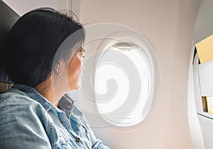 Asian Woman sitting at window seat in airplane and look outside