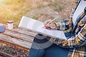 Asian woman sitting and writing in the garden