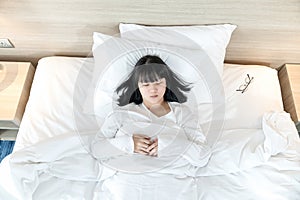 Asian woman sleeps on white bed after exhausted and tried all day
