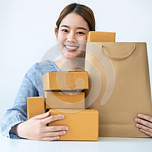 Asian woman small business owner smiling with many parcel of box to preparing order delivery to customer at home
