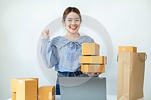 Asian woman small business owner standing and smiling to raise arm when job finished after receive order