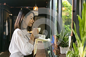 Asian woman smelling and drinking hot coffee with feeling good i