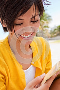 Asian woman smiling and reading the Bible at the Beach