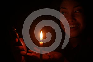 Asian woman smiling to her cellphone with candle in the dark night