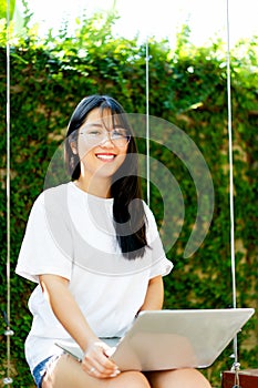 Asian woman smiling while working on her laptop outside the office, at home, working in the park. work holiday at