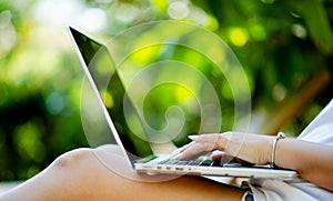 Asian woman smiling while working on her laptop outside the office, at home, working in the park. work holiday at