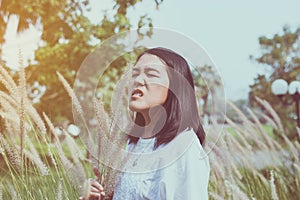 Asian woman sneezes because of allergy with flower at outdoor
