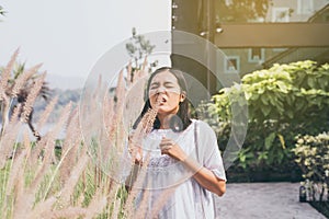 Asian woman sneezes because of allergy with flower at outdoor photo