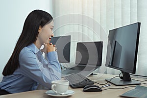Asian woman software developers sitting in front of computers looking at computer codes on the screen