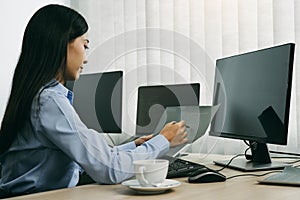Asian woman software developers sitting in front of computers looking at computer codes on the screen