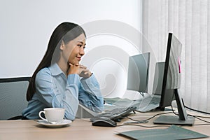 Asian woman software developers sitting in front of computers looking at computer codes on the screen