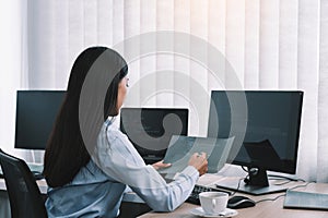 Asian woman software developers sitting in front of computers looking at computer codes on the screen