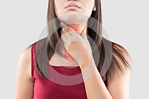 Asian woman with a sore throat or thyroid gland against the gray background. Acid reflux or Heartburn.