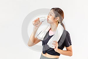 Asian woman in sport clothing and towel on neck drink bottle of water after exercise and fitness