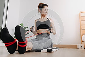 Woman in sport wears do Resistance Band Seated Pronated Row in her room. photo
