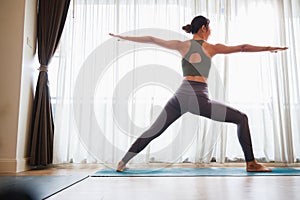 Asian woman in sports clothing doing yoga at home to quarantine herself from Covid-19, New normal lifestyle concept. Healthy