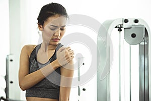 Asian woman in sportswear having shoulder pain