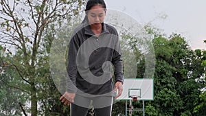 Asian woman in sportswear playing basketball at outdoor playground. Female basketball players practice outdoors on local courts.