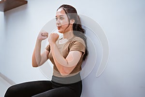 asian woman squating against the wall at home