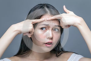 Asian woman squeezing spot on forehead