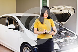 Asian woman staff with clipboard checking car