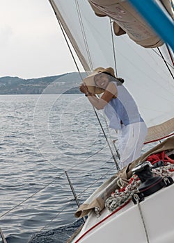 Asian woman standing on deck of a heeling sailboat