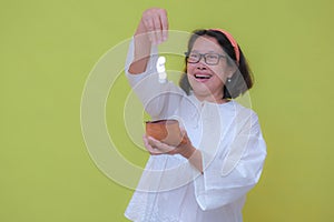 A woman smilingly dropping some Rupiah coins into her wallet photo