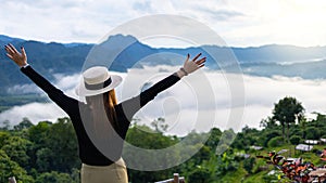 Asian woman standing with hands up achieving the top. Happy celebrating winning success woman