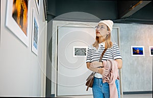 Asian woman standing she looking art gallery in front of colorful framed