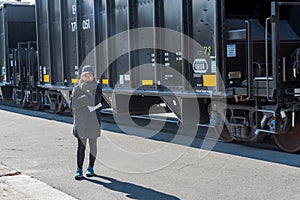 Asian woman standing next to coal cars